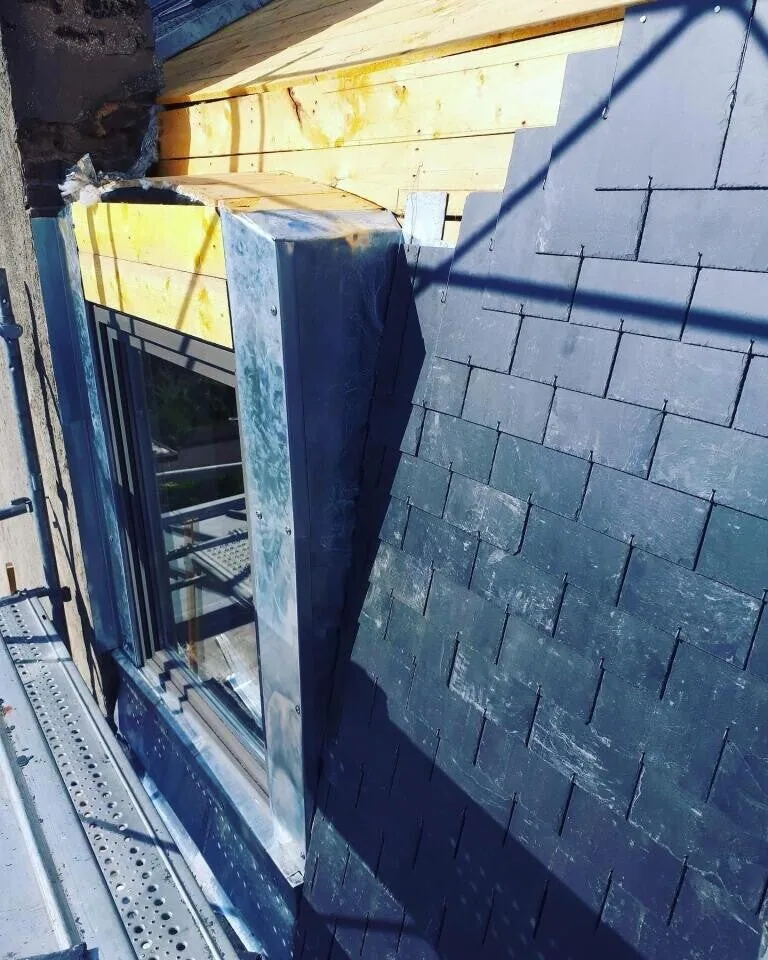 Couverture en ardoise avec lucarne et habillage zinc en cours de pose